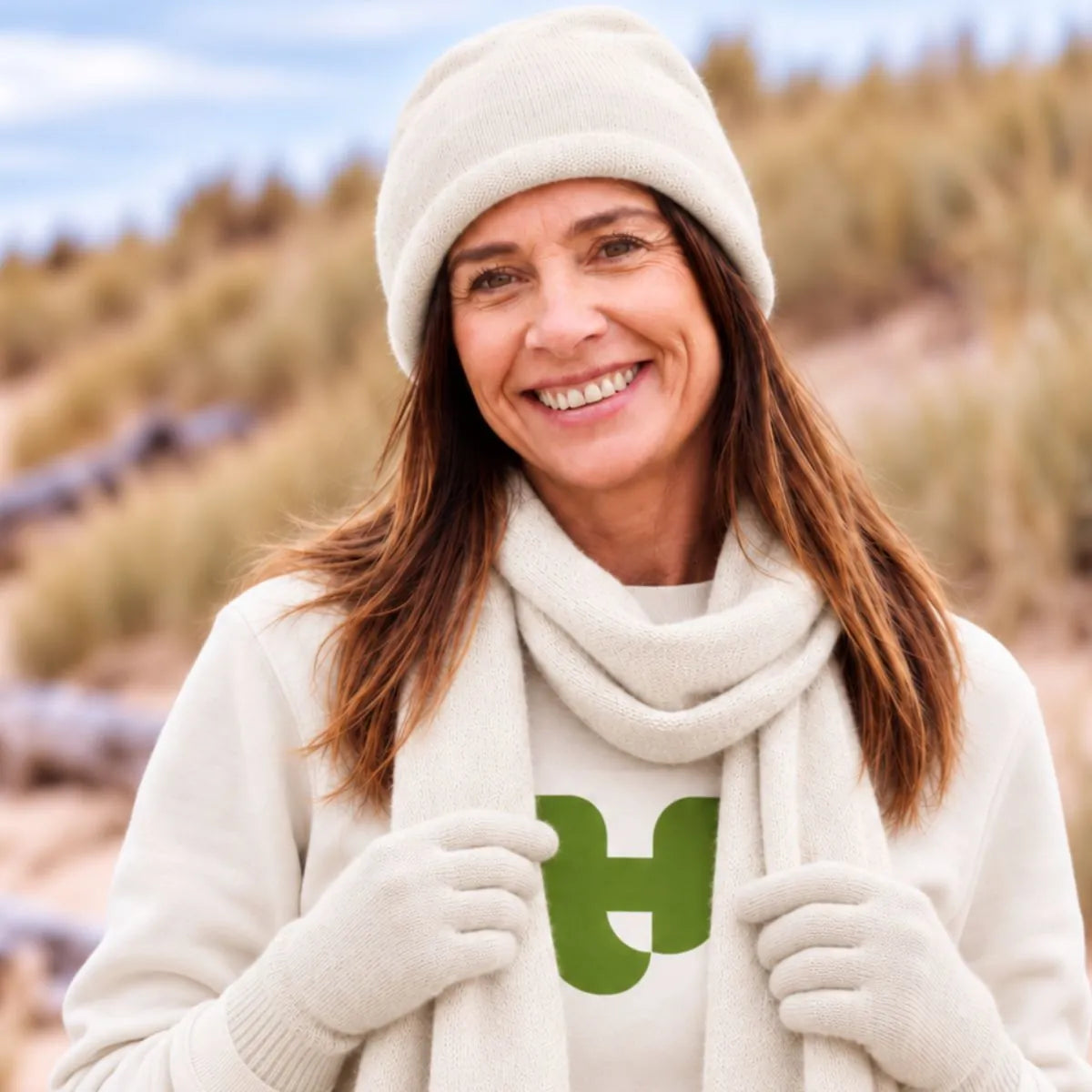 Femme souriante portant le bonnet en cachemire blanc cassé avec l'écharpe et les gants assortis