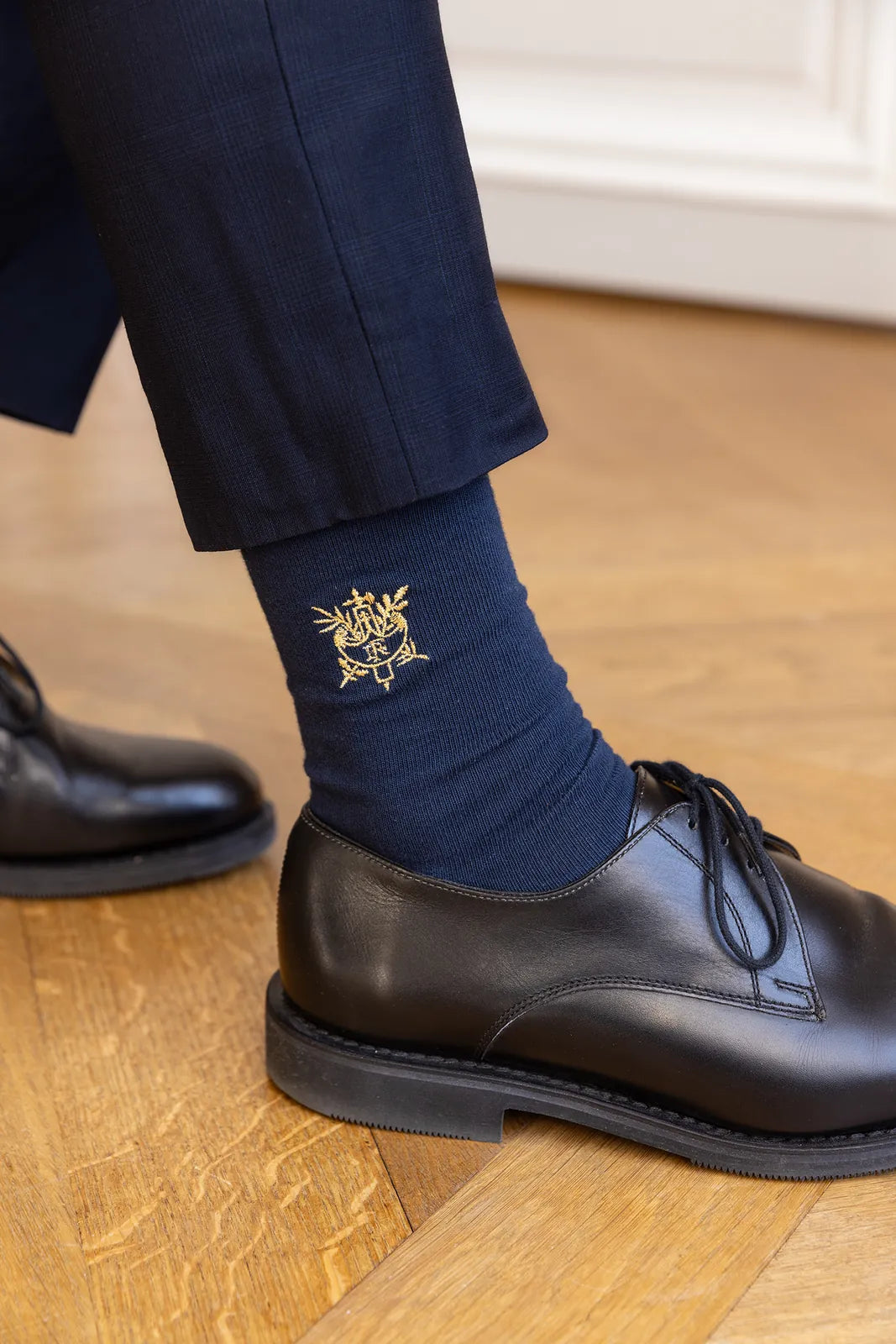 Chaussettes brodées Élysée portées avec un costume et des derbies noirs