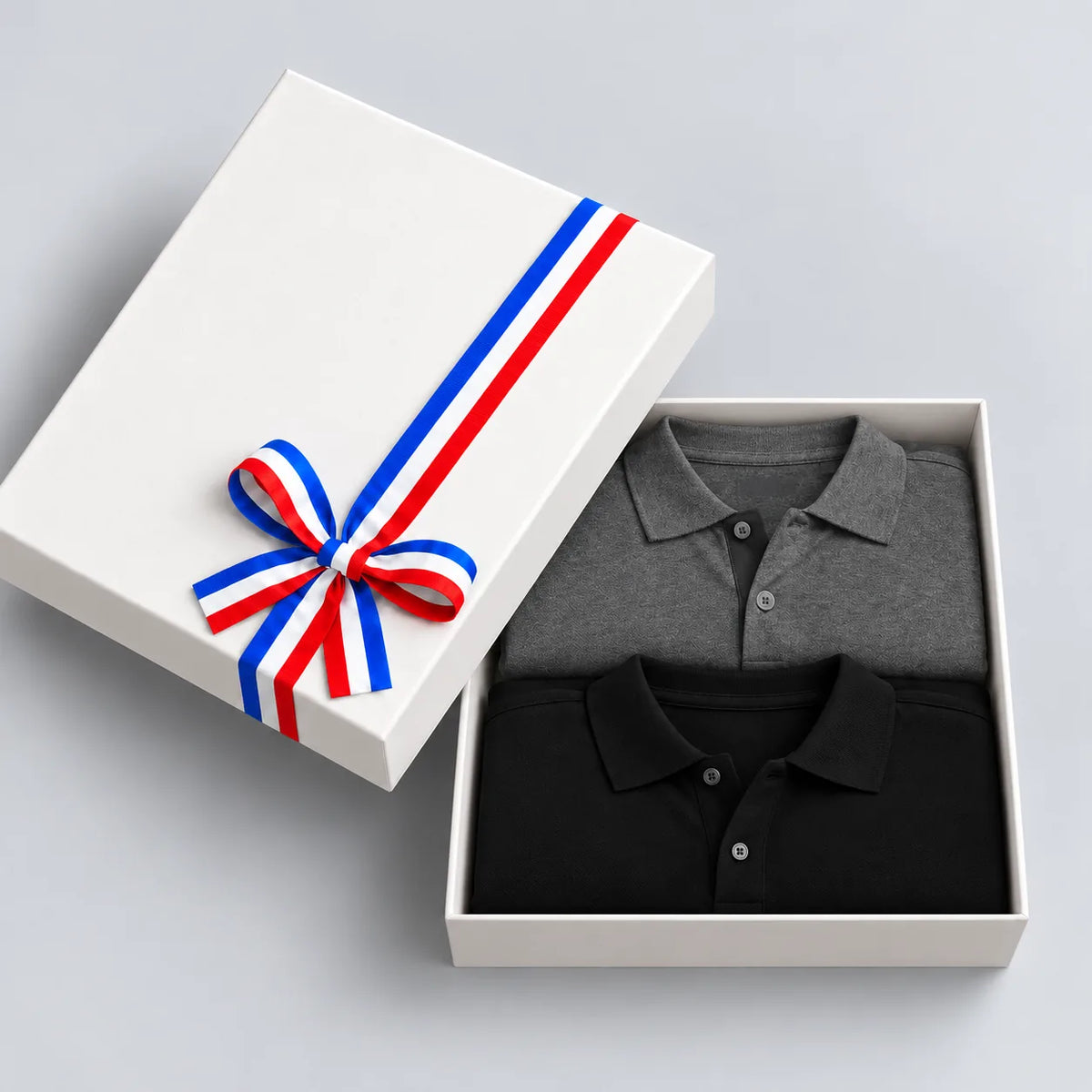 Coffret cadeau ouvert avec 2 polos homme en coton bio, noir et gris anthracite, couvercle à ruban tricolore