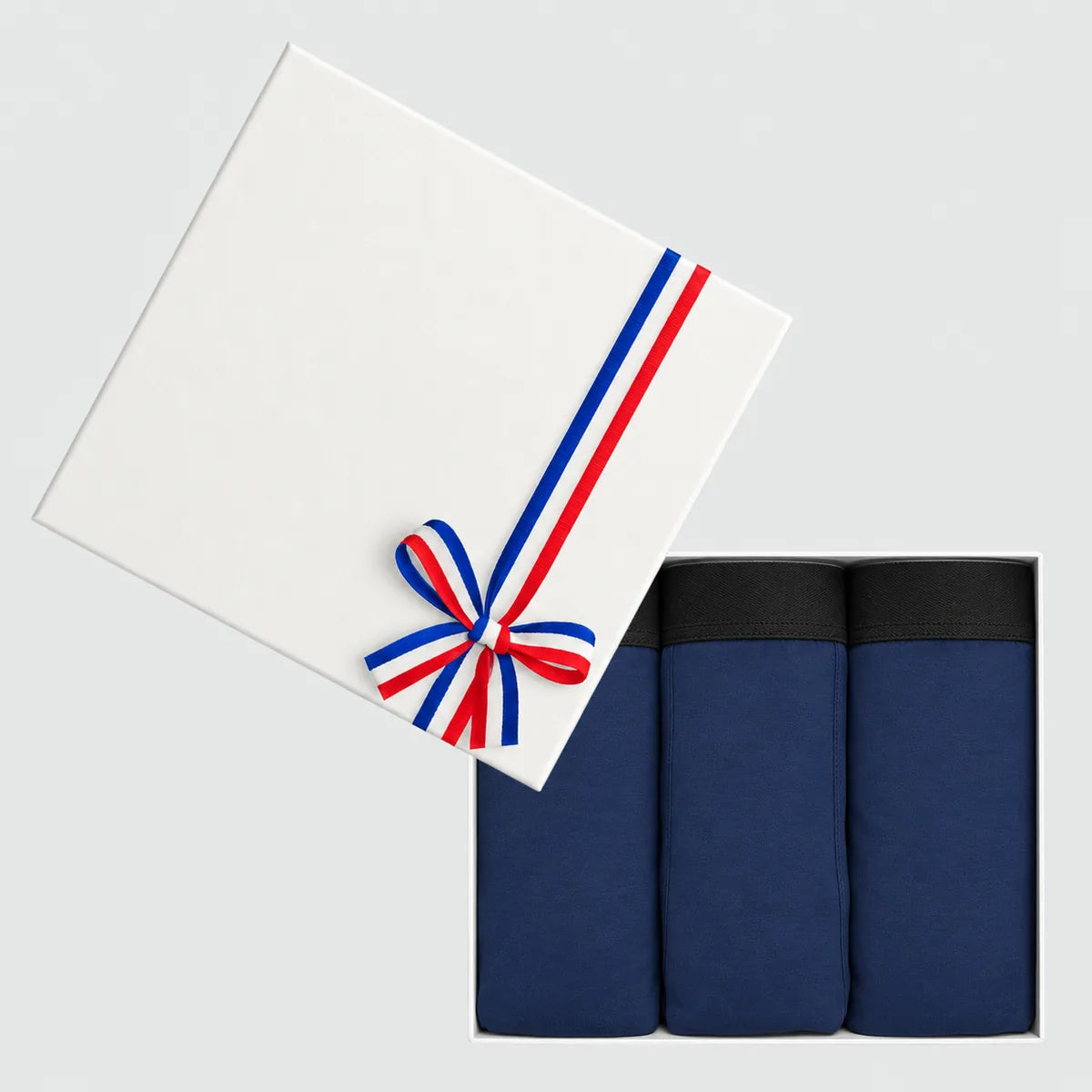 Coffret cadeau blanc ouvert avec 3 boxers homme bleu marine en coton bio, couvercle noué d'un ruban tricolore