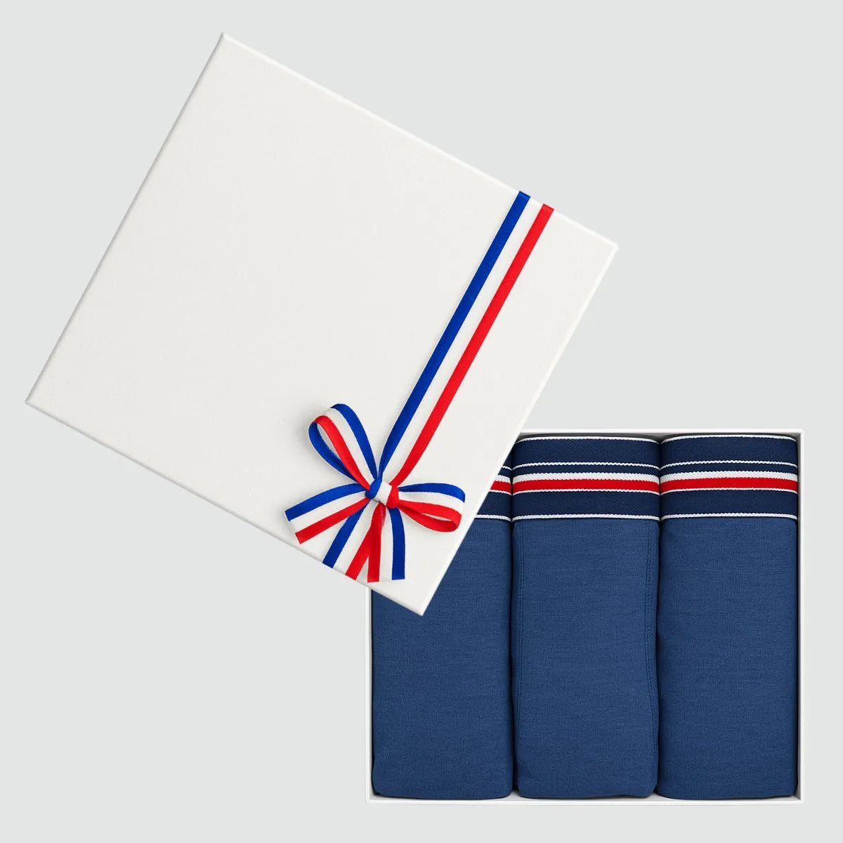 Coffret cadeau ouvert avec 3 slips homme bleu marine en coton bio, couvercle blanc à ruban tricolore