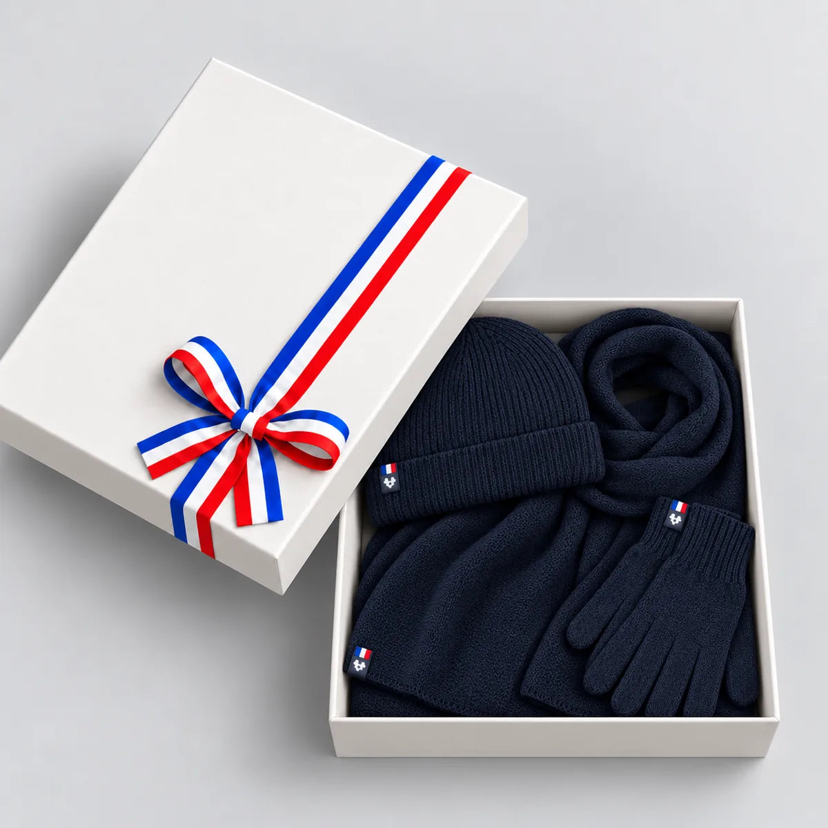 Coffret cadeau ouvert avec écharpe, bonnet et gants bleu marine en laine mérinos, couvercle à ruban tricolore