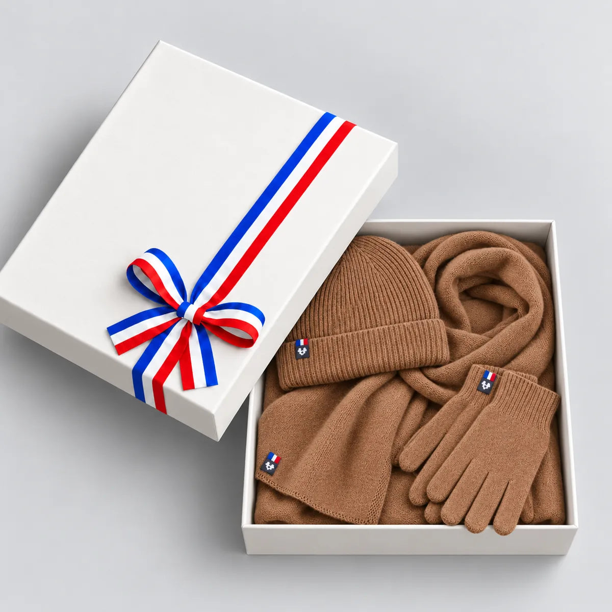 Coffret cadeau ouvert avec écharpe, bonnet et gants camel en laine mérinos, couvercle à ruban tricolore