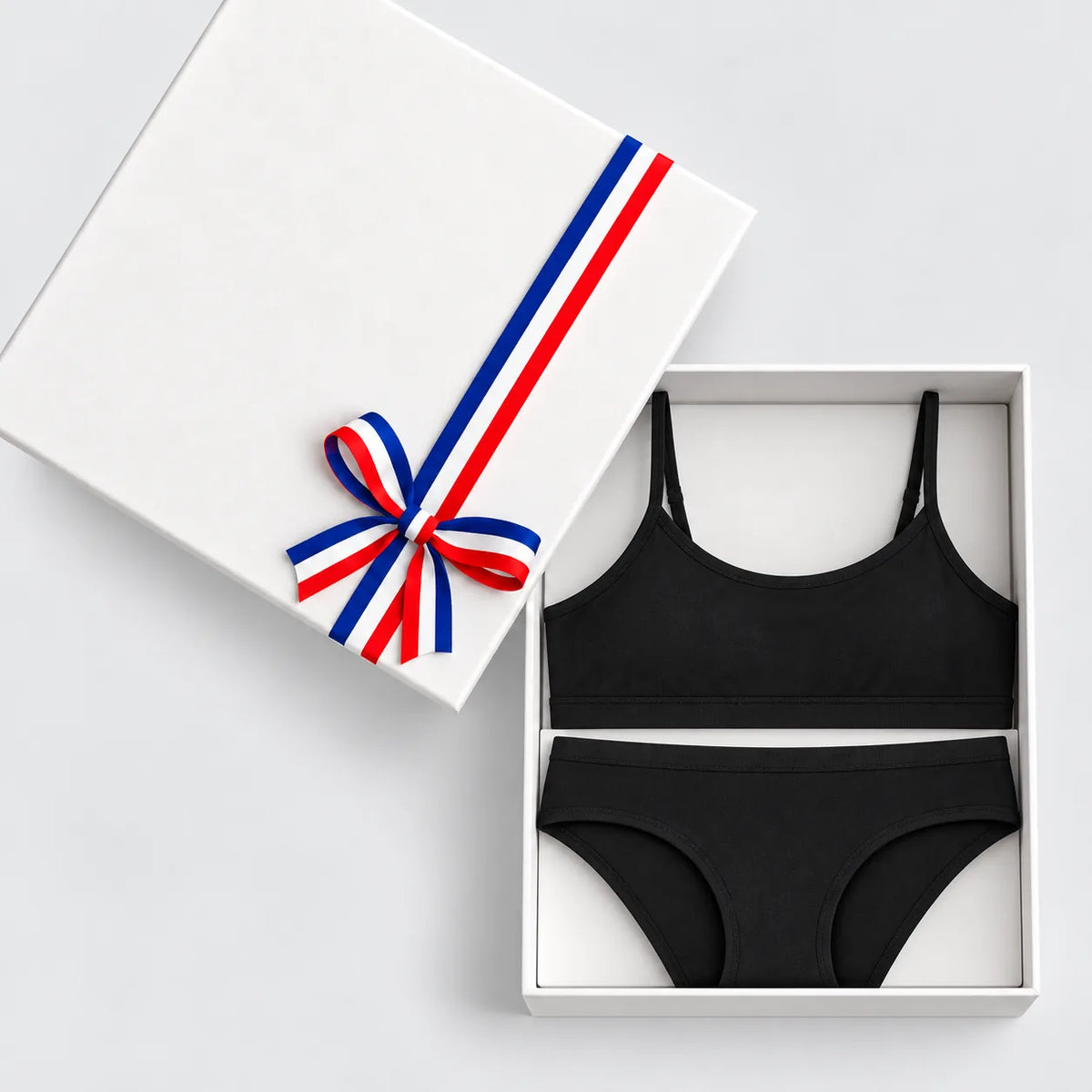 Coffret cadeau lingerie noire ouvert : brassière à fines bretelles et culotte en coton et modal, ruban tricolore