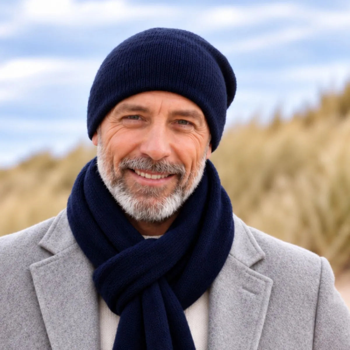Homme barbu en manteau gris portant le bonnet et l'écharpe en cachemire bleu marine