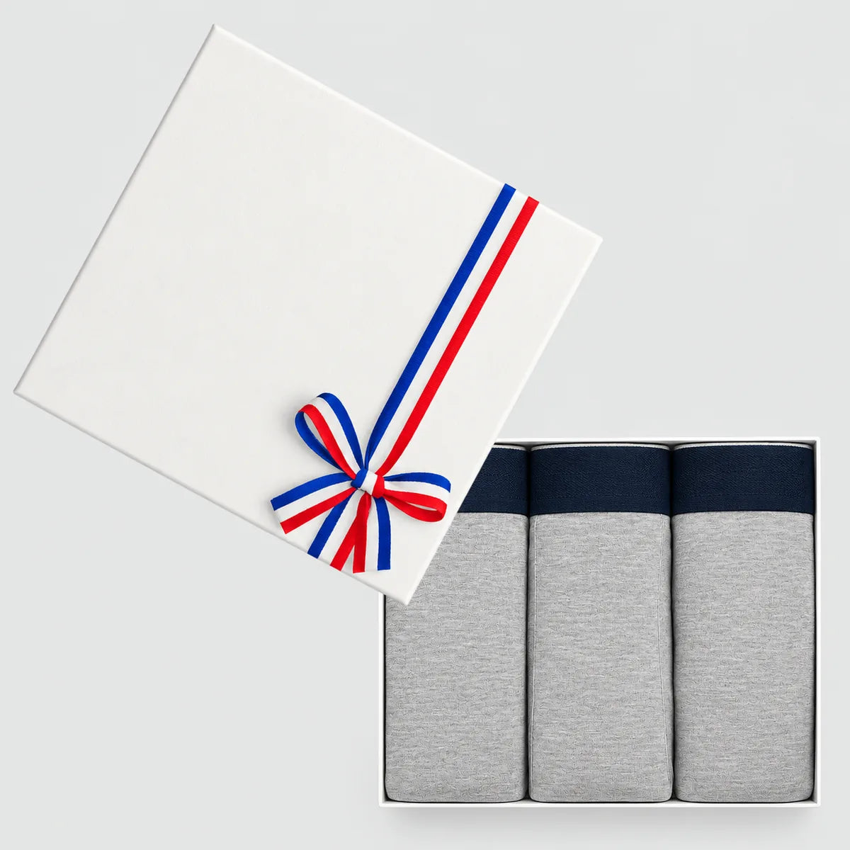 Coffret cadeau blanc ouvert avec 3 boxers homme gris chiné en coton bio, couvercle noué d'un ruban tricolore