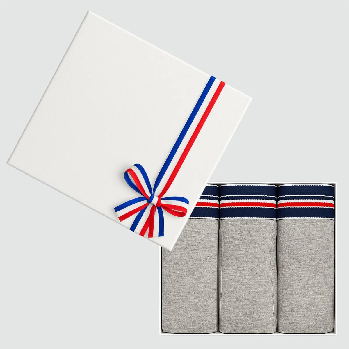 Coffret cadeau ouvert avec 3 slips homme gris chiné en coton bio, couvercle blanc à ruban tricolore
