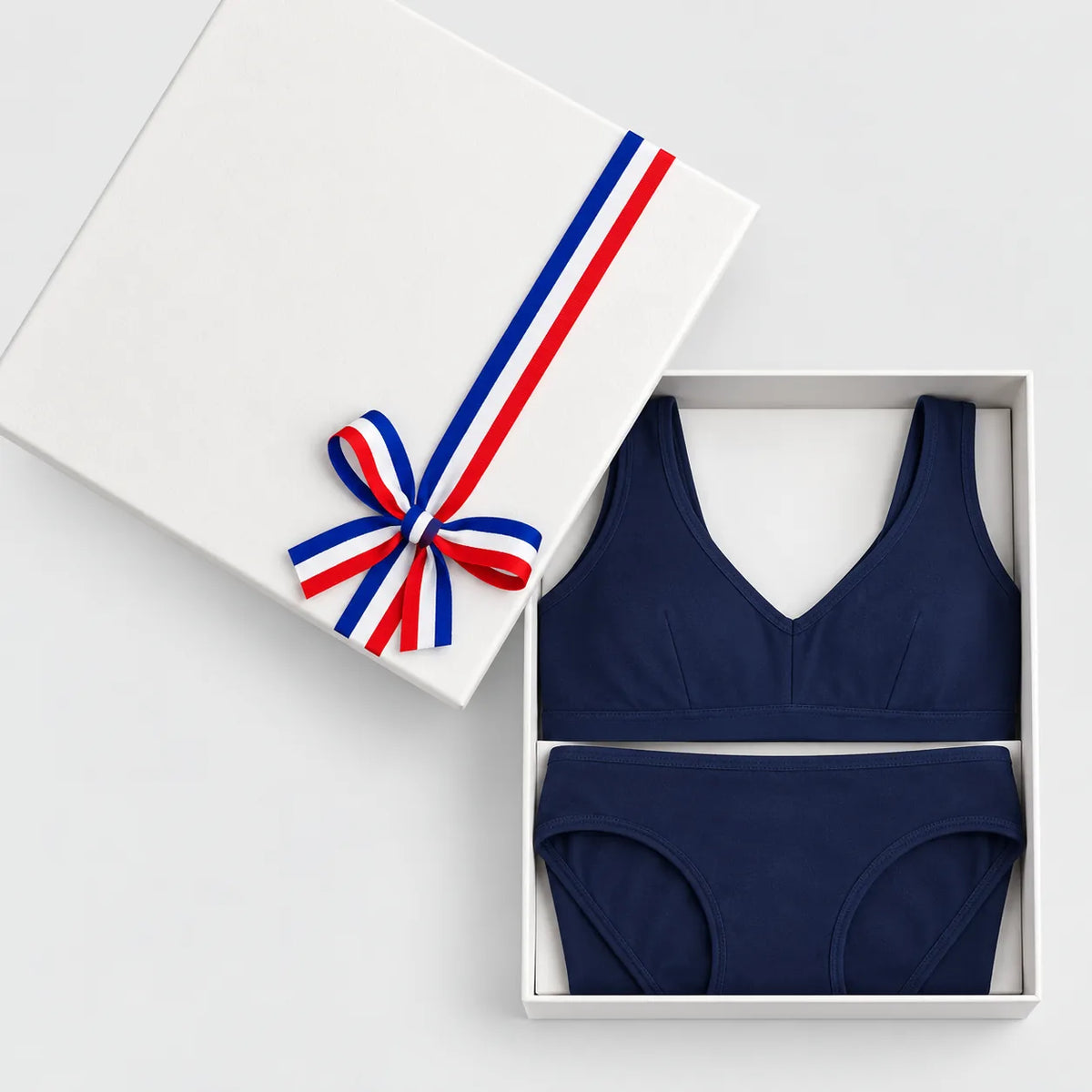 Coffret cadeau lingerie bleu marine ouvert : brassière à pince et culotte en coton bio, couvercle à ruban tricolore