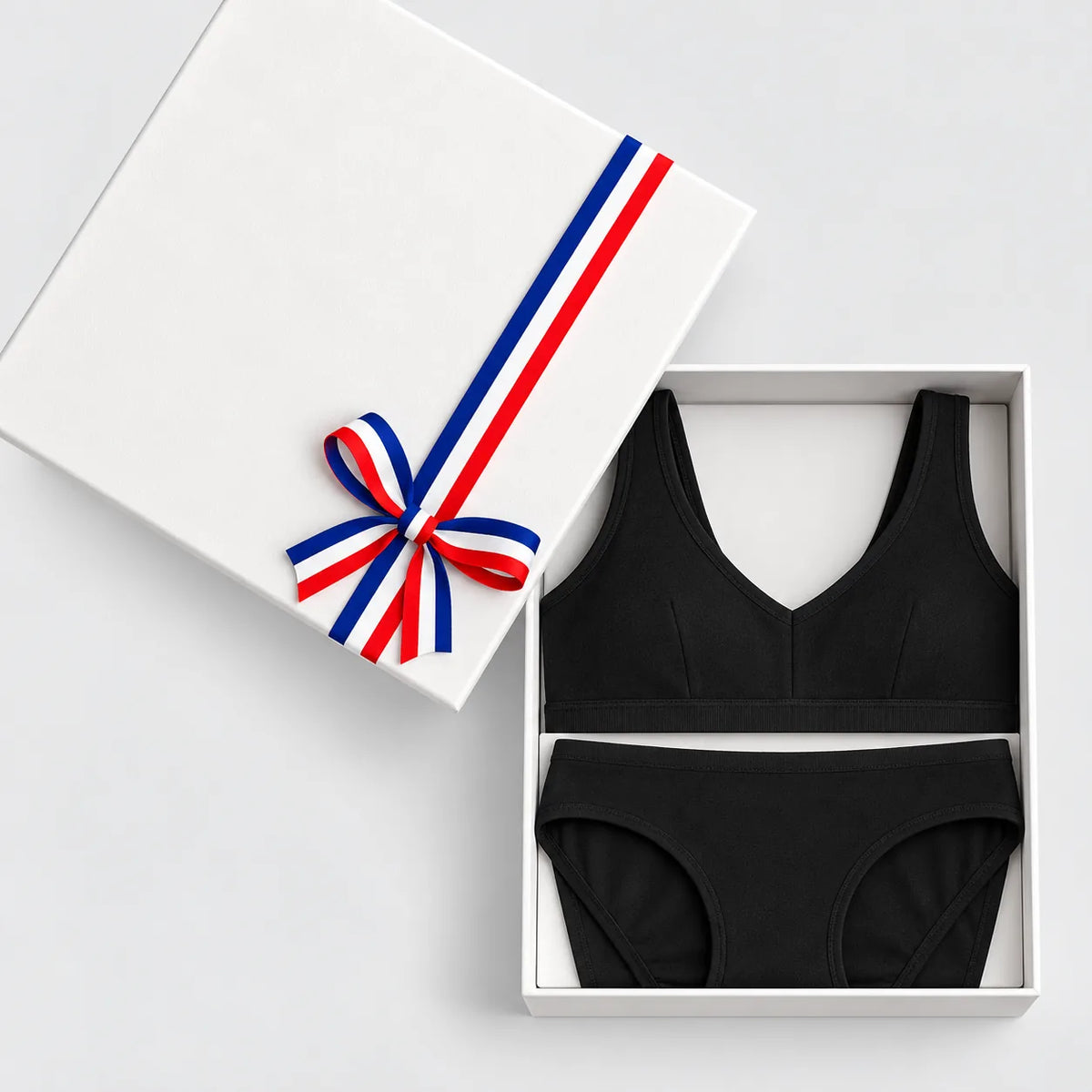 Coffret cadeau lingerie noire ouvert : brassière à pince et culotte en coton bio, couvercle à ruban tricolore