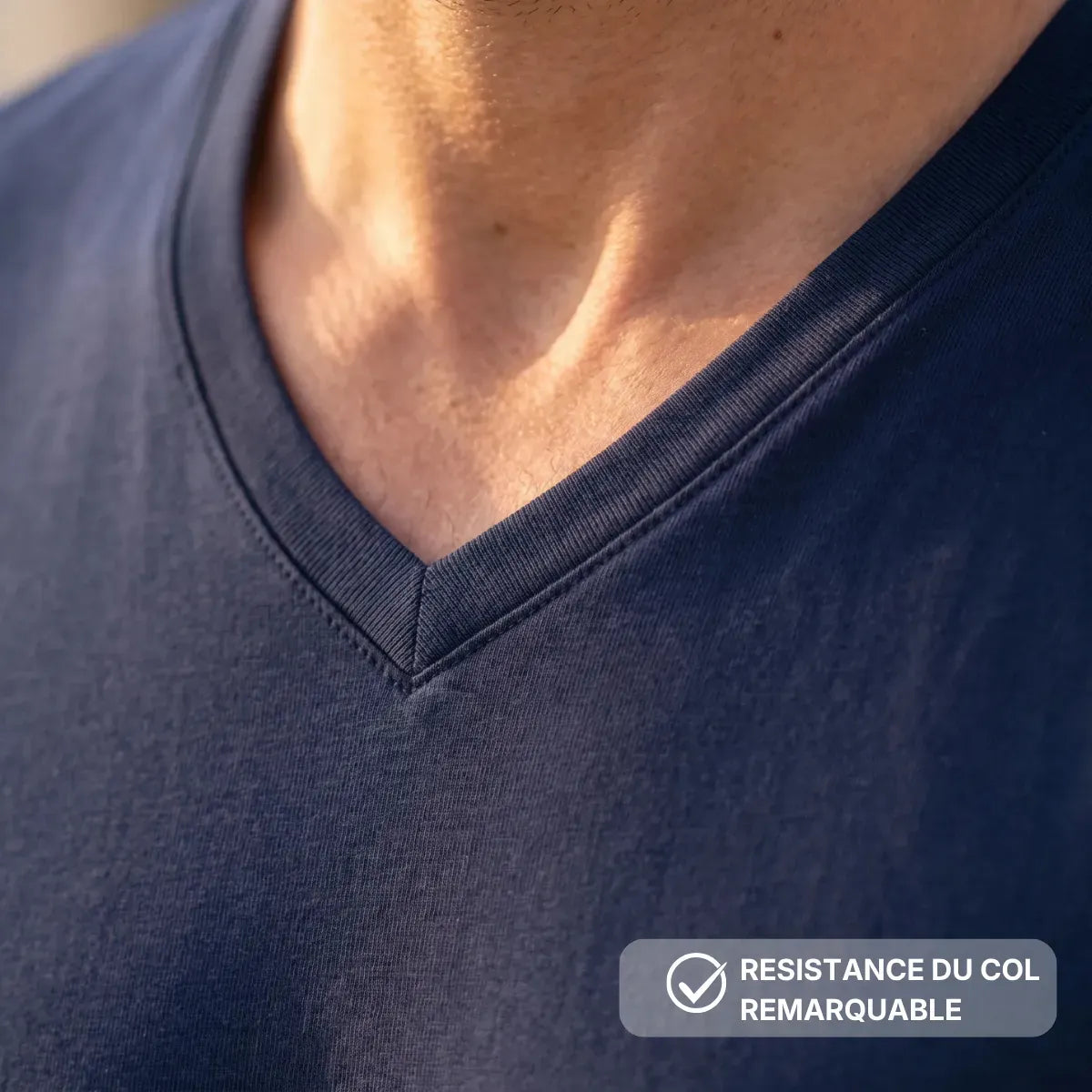 Gros plan sur le col V du t-shirt bleu marine, coupé dans la matière principale